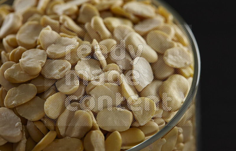 Crushed beans in a glass jar on black background