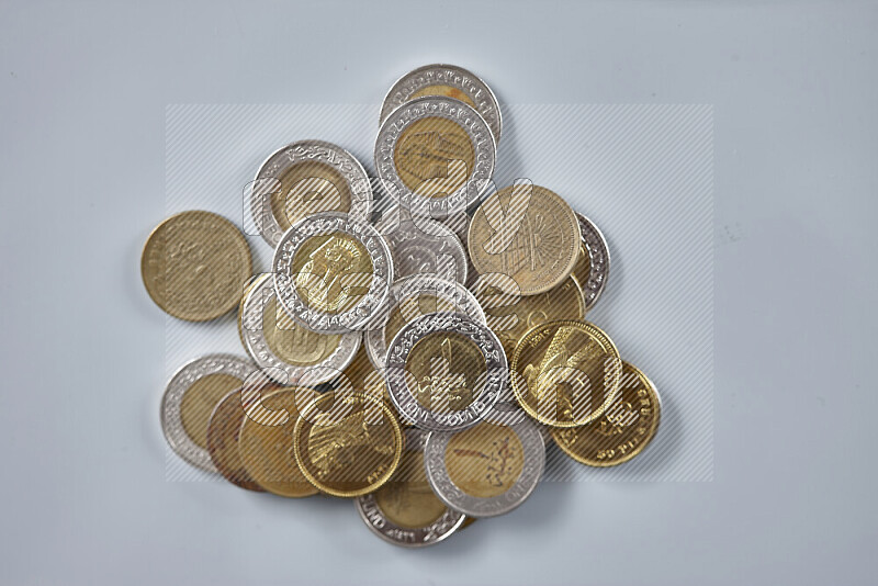 A close-up of scattered mixed Egyptian coins such as One pound, 50 and 25 piasters on grey background