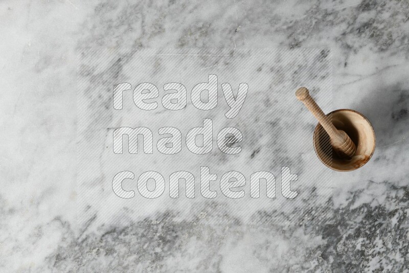 وعاء فخاري بيج مع ملعقة عسل خشبية بداخله على خلفية من الرخام الرمادي