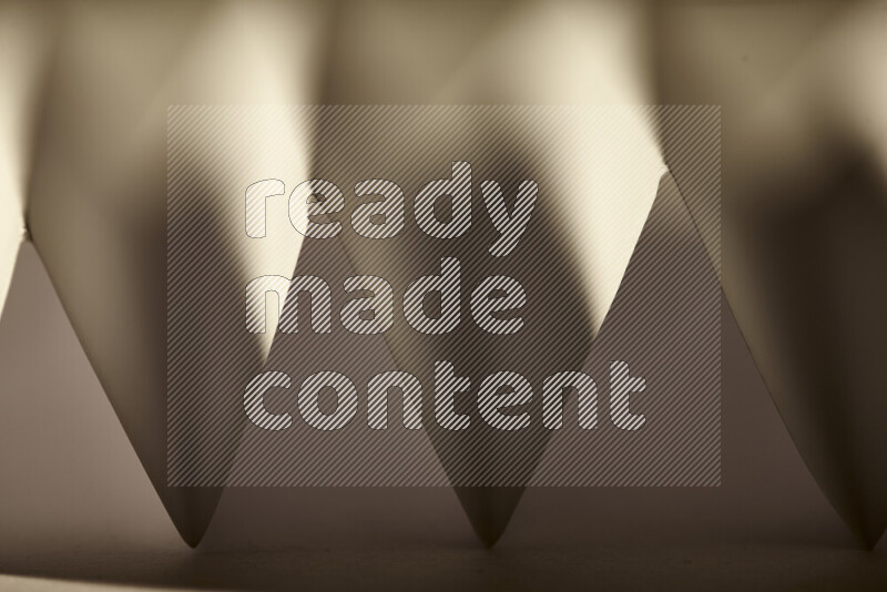 صورة مجردة مقربة تظهر طيات ورقية هندسية حادة بتدرجات الوان دافئة