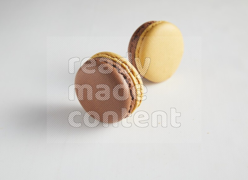 45º Shot of two Yellow and Brown Chai Latte macarons on white background