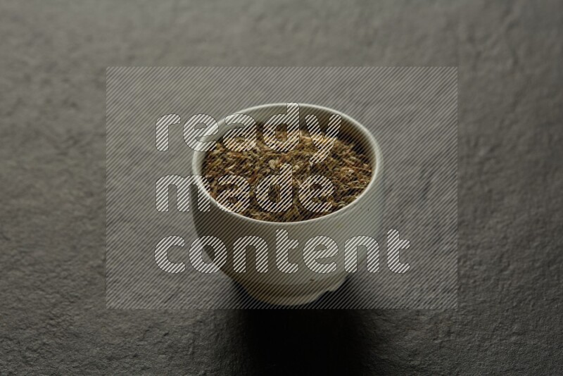 white ceramic round sauce bowl filled with herbs on grey textured countertop