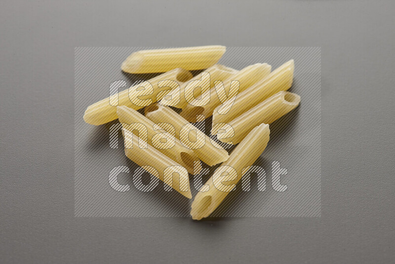 Mini penne pasta on grey background