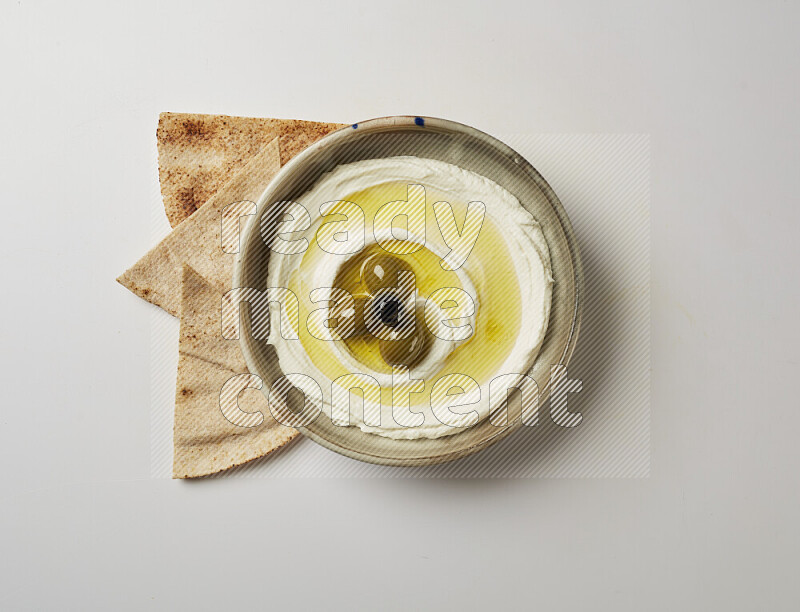 Lebnah garnished with whole olives in a grey pottery plate on a white background