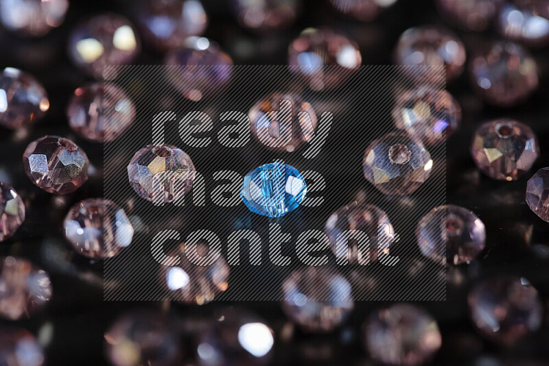 Rose and blue transparent crystal beads scattered on a black background
