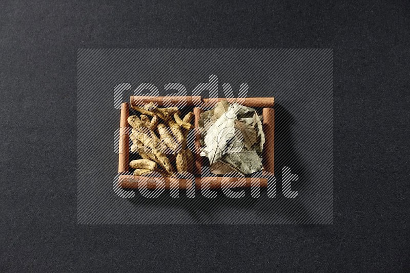 2 squares of cinnamon sticks full of bay laurel leaves and turmeric fingers on black flooring