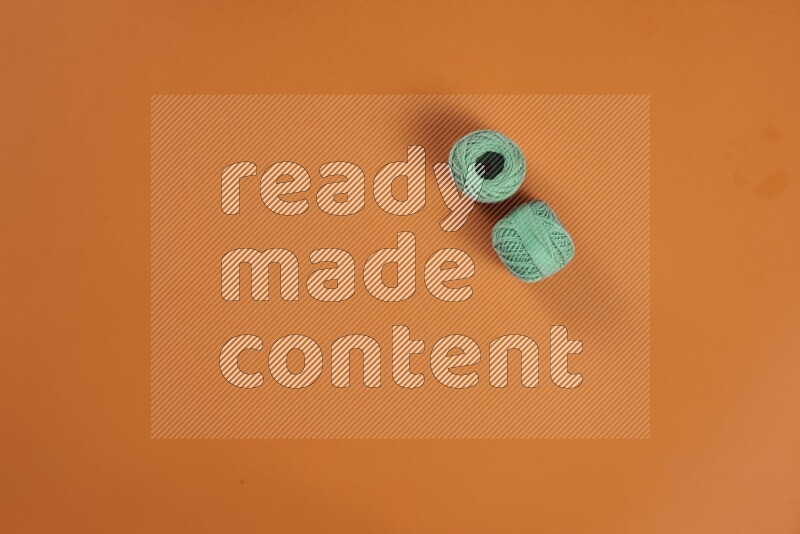 مجموعة من أدوات الخياطة والتفصيل خضراء وبرتقالية اللون على خلفية برتقالية