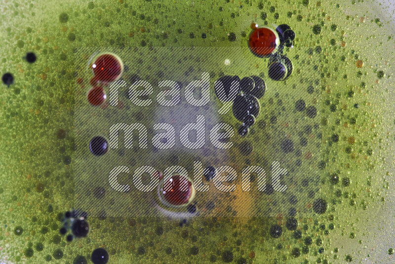 لقطات مقربة لقطرات ألوان مائية حمراء وخضراء وزرقاء على سطح الزيت على خلفية خضراء
