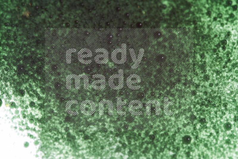 لقطات مقربة لقطرات ألوان مائية خضراء على سطح الزيت على خلفية بيضاء