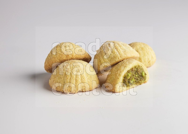 Five Pieces of Maamoul filled with pistachio  paste one of them is cut direct on white background