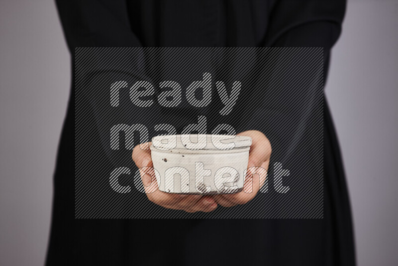 A woman in black abaya holding different pottery essentials in different positions