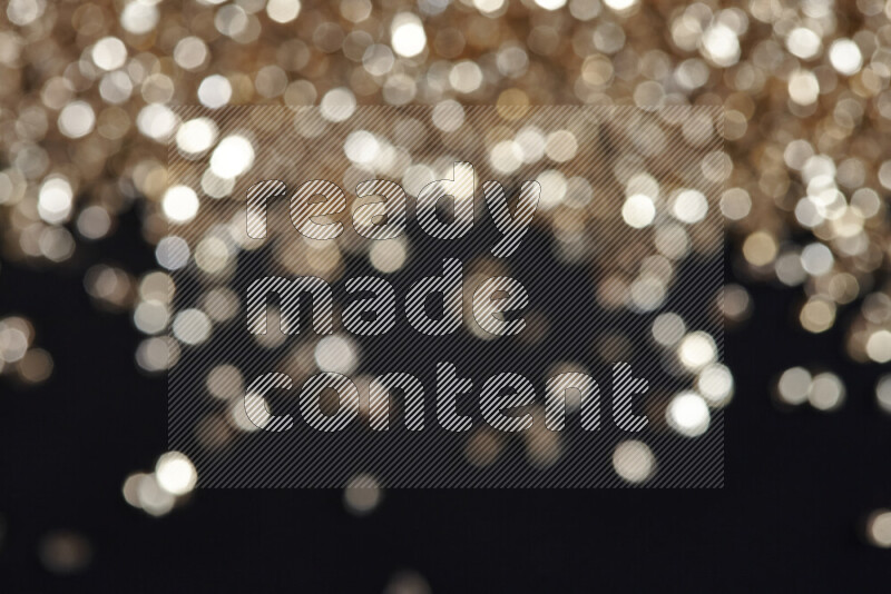 قطع زجاجية ذهبية لامعة متناثرة على خلفية سوداء