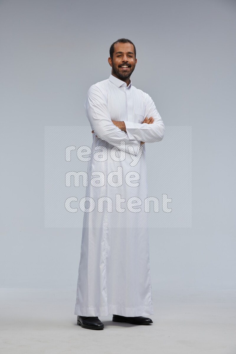 Saudi man wearing Thob standing with crossed arms on Gray background