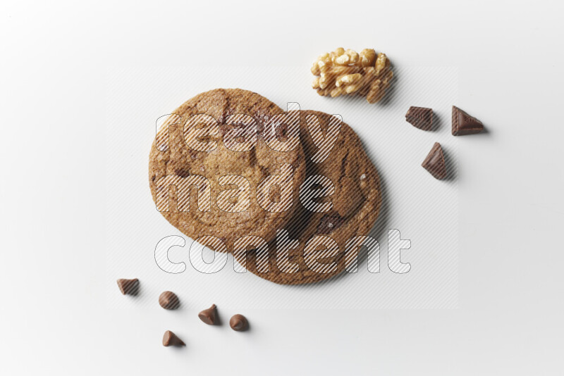 Chocolate chips cookies with chocolate and walnuts beside it on a white background