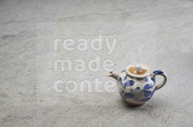A pottery teapot on grey marble background