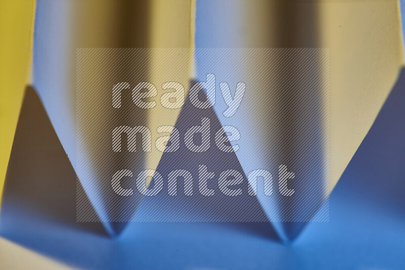 A close-up abstract image showing sharp geometric paper folds in blue gradients and warm tones