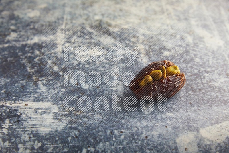 pistachios stuffed madjoul date on a rustic blue background