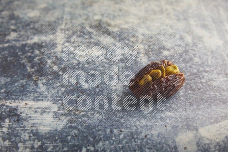 pistachios stuffed madjoul date on a rustic blue background
