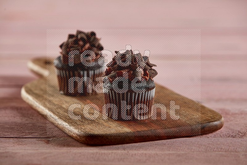 Chocolate mini cupcake topped with chocolate curls on a wooden board