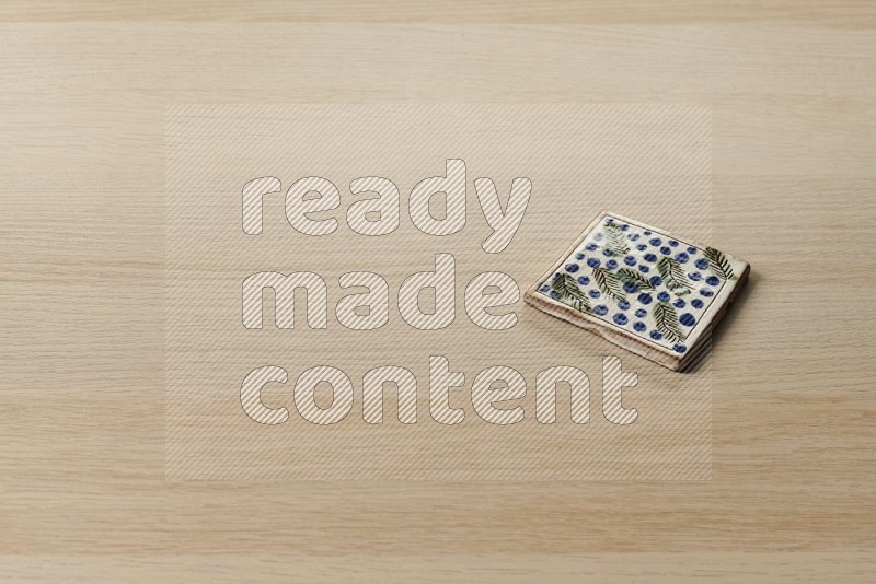 Pottery coaster\ tile on oak wooden flooring, 45 degrees