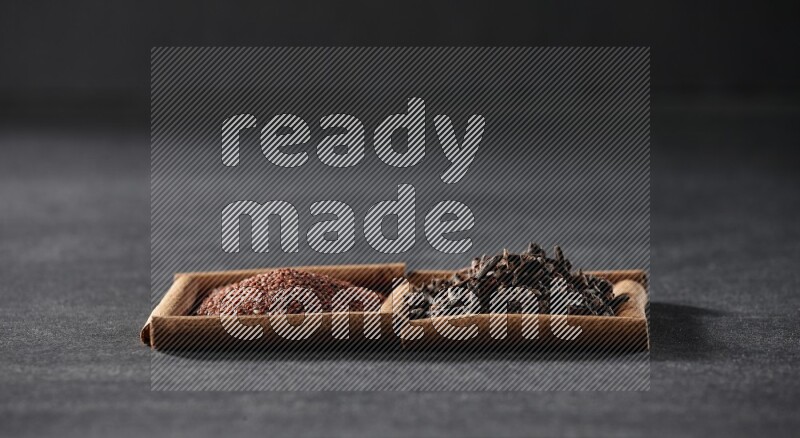 2 squares of cinnamon sticks full of garden cress and cloves on black flooring