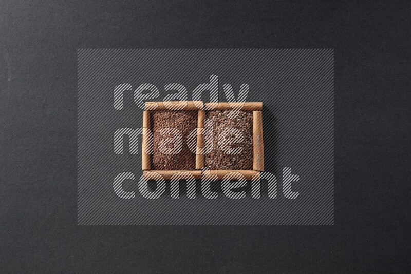 مربعان من أعواد القرفة ممتلئان بحب الرشاد وبذور الكتان علي خلفية سوداء