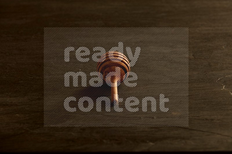 Wooden honey dipper on black slate background