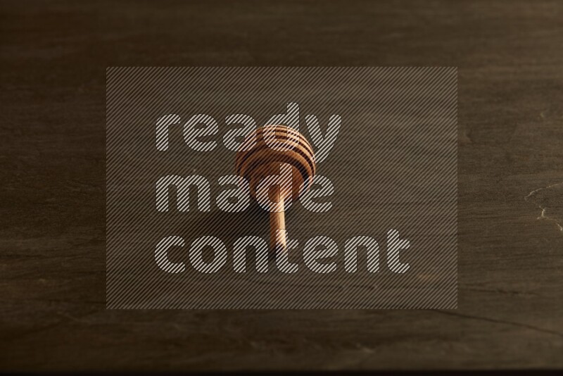 Wooden honey dipper on black slate background