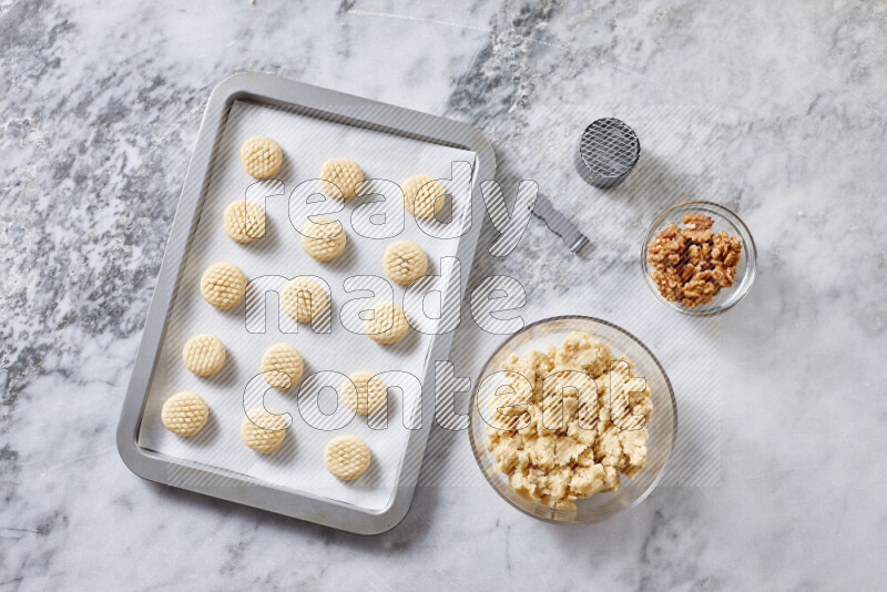 كحك خطوة بخطوة بمكوناته سمن، سكر، دقيق، سمسم، خميرة، ماء ونكهة الكحك على خلفية رخام رمادي