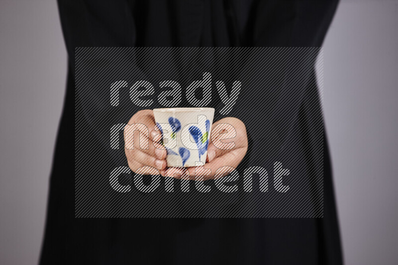 A woman in black abaya holding different pottery essentials in different positions