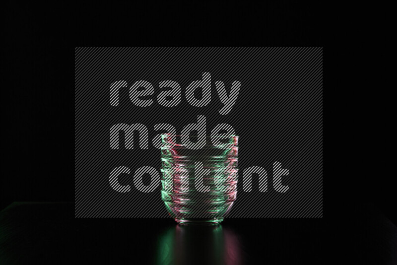 Glassware with rim light in red and green against black background