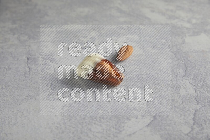 Almond stuffed date coved with white chocolate on a light grey background