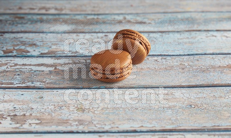 45º Shot of two Brown Coffee macarons on light blue wooden background