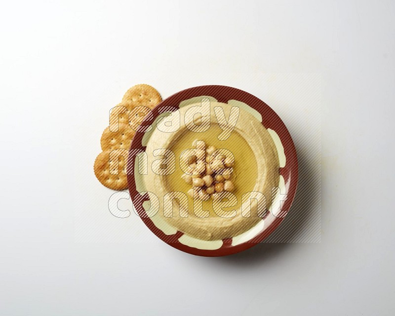 Hummus in a traditional plate garnished with roasted chickpeas  on a white background