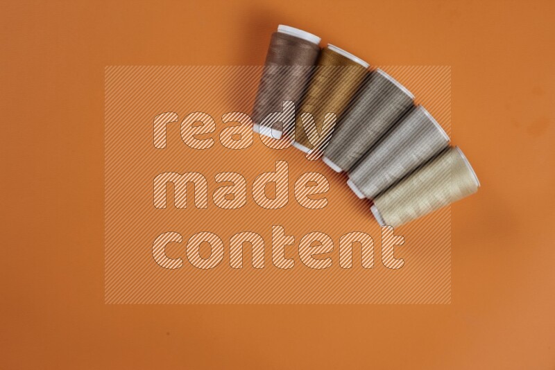 مجموعة من أدوات الخياطة والتفصيل بنية اللون على خلفية برتقالية