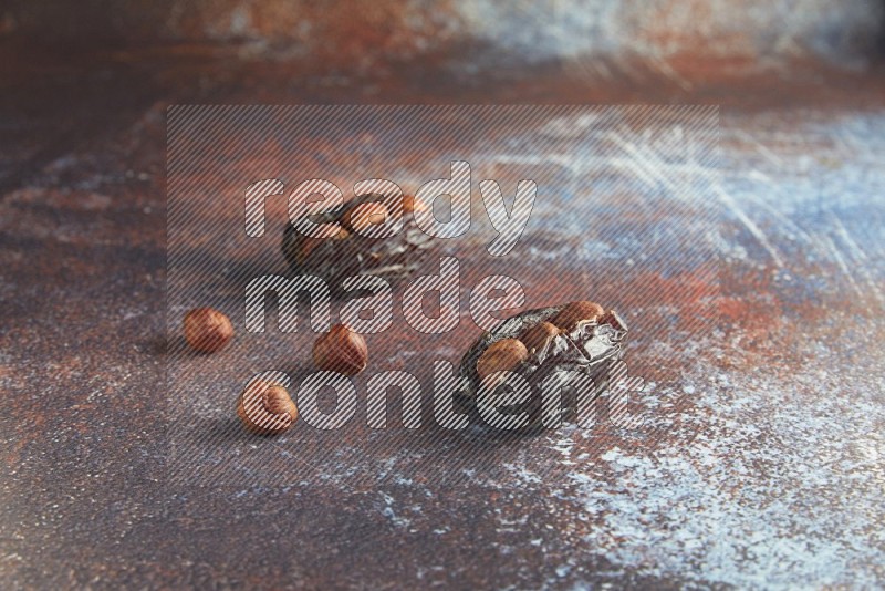 two hazelnut stuffed madjoul dates on a rustic reddish background