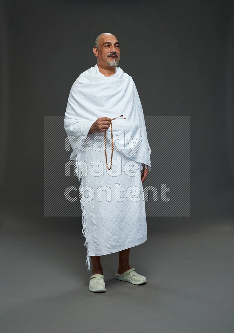 A man wearing Ehram Standing holding rosary on gray background