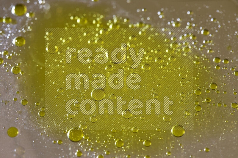 Close-ups of abstract yellow watercolor drops on oil Surface on yellow background