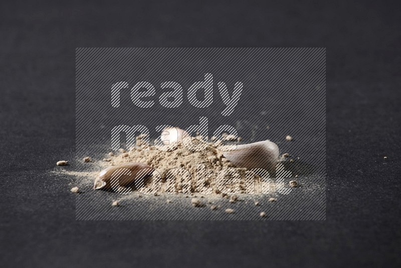 Garlic powder and garlic bulb and cloves on a black flooring in different angles