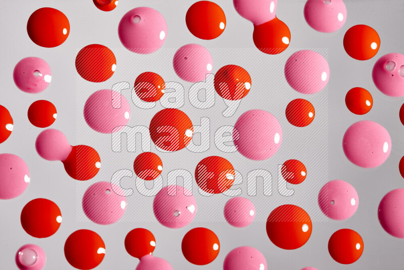 Close-ups of abstract pink and red paint droplets on the surface