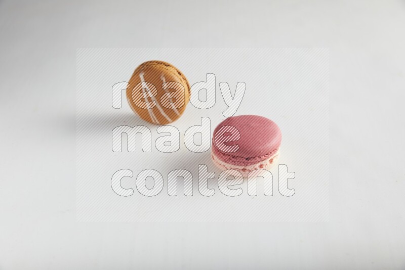 45º Shot of of two assorted Brown Irish Cream, and Pink Litchi Raspberry macarons on white background
