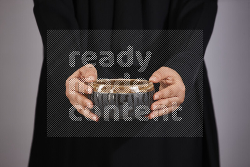 A woman in black abaya holding different pottery essentials in different positions