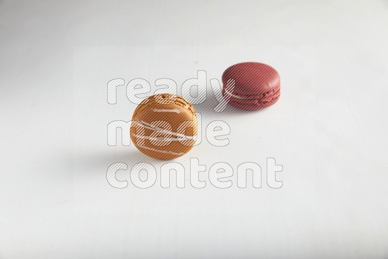 45º Shot of of two assorted Brown Irish Cream, and Red Velvet macarons on white background