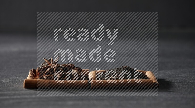 مربعان من أعواد القرفة ممتلئان باليانسون النجمي والشاي الأسود علي خلفية سوداء