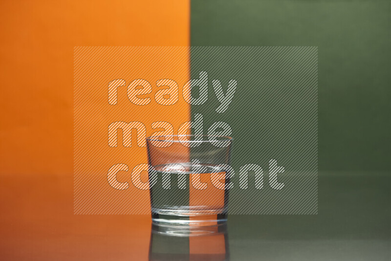 The image features a clear glassware filled with water, set against orange and dark green background