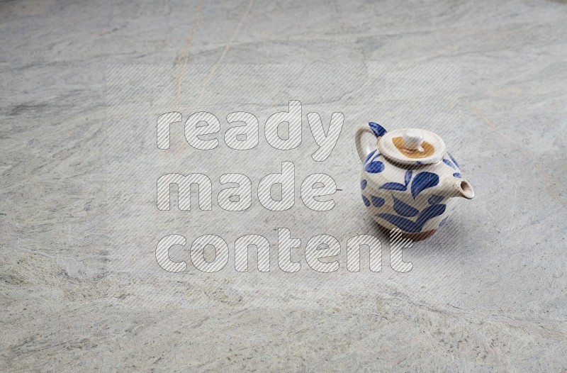 A Pottery Teapot On Grey Marble Flooring