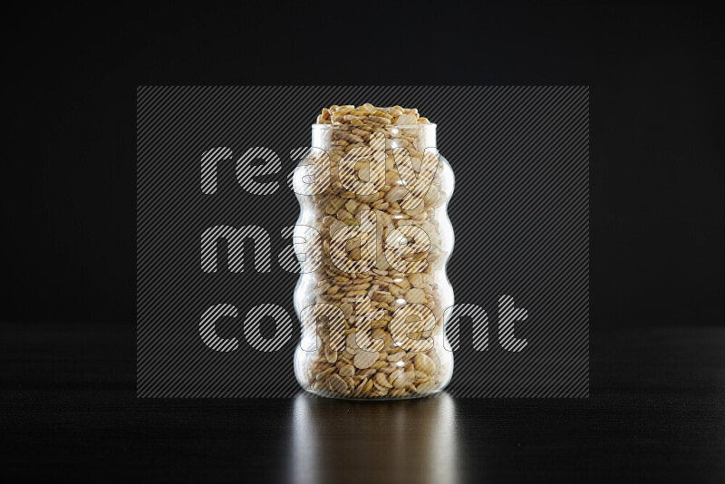 Crushed beans in a glass jar on black background