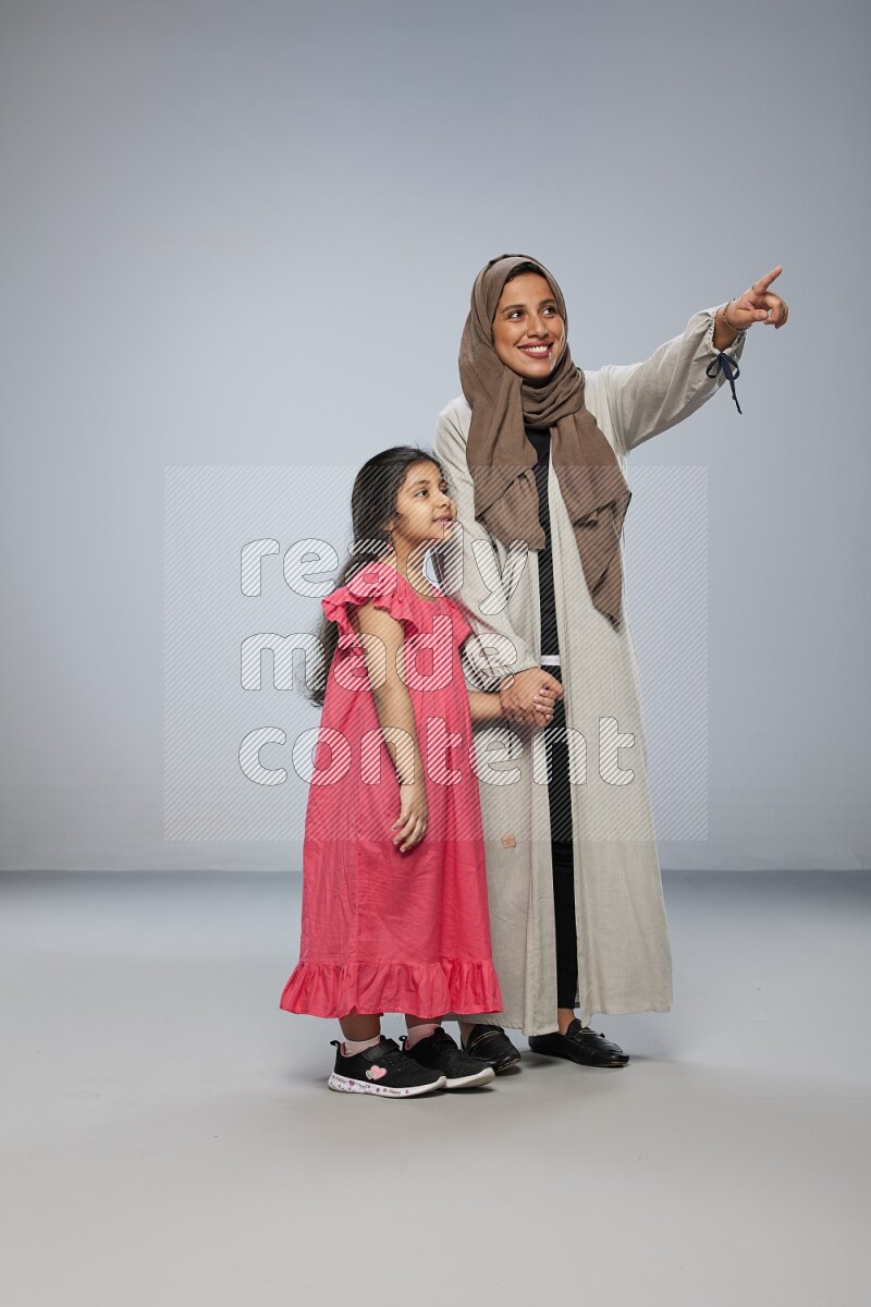 A girl and her mother interacting with the camera on gray background