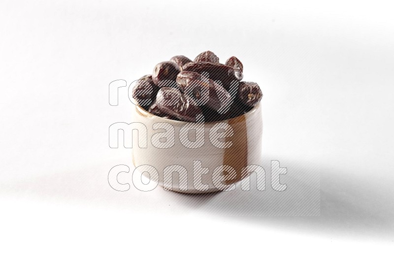 Dates in a beige pottery bowl on white background