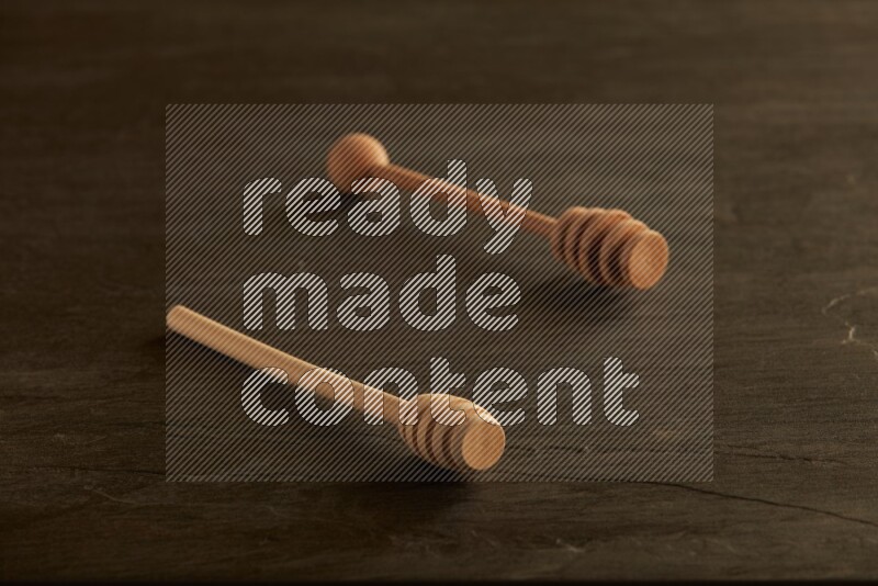 Wooden honey dipper on black slate background